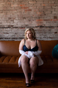 woman sitting on couch in lingerie under a white button down shirt