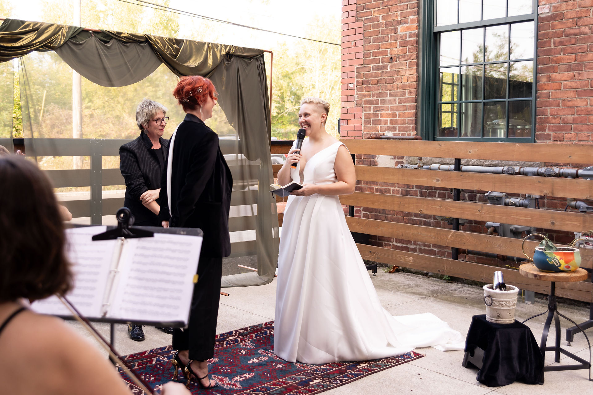 bride in white dress holding microphone during lgbtq wedding ceremony