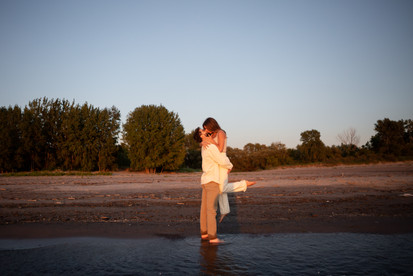 engaged couple on a beach man picks up woman