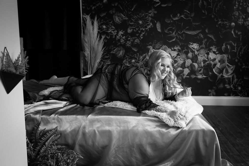 plus size boudoir model laying on bed playing with hair