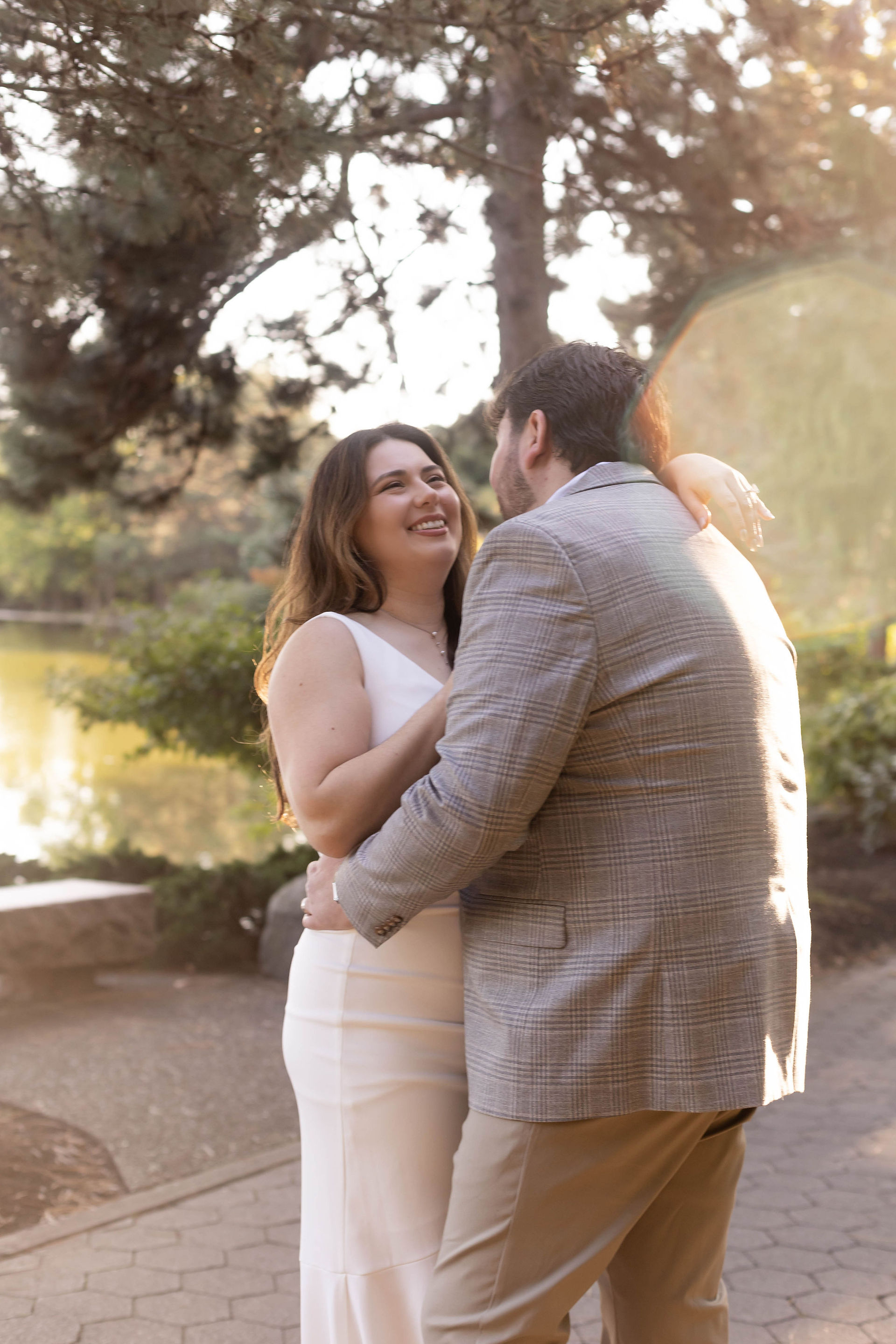 couple hugs as sun beams around them in a garden