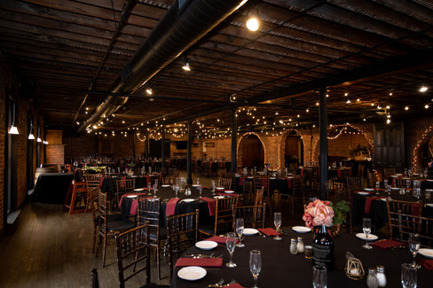 dark wedding reception room with twinkle lights, brick arches and round tables