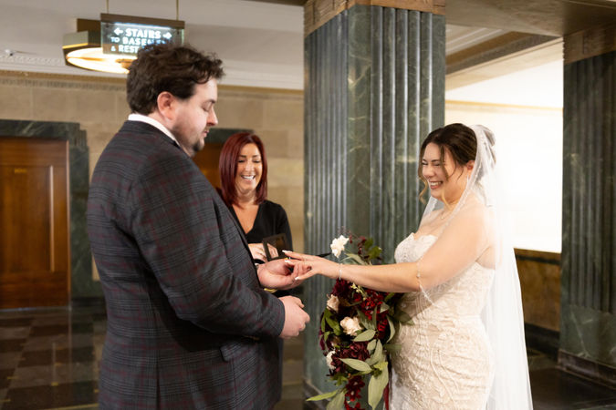 bride with huge smile as her groom slips her ring on during ceremony
