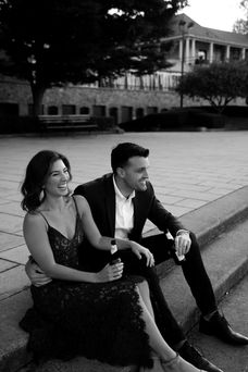 couple sits on steps in formal wear laughing and holding beers
