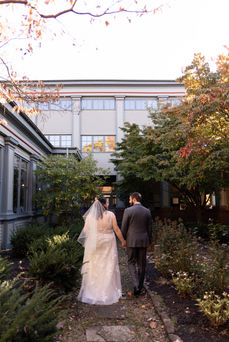 bride and groom walk away from the camera looking at each other in garden of Roycroft Inn