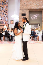 bride and groom first dance in front of guests with monogram projected onto the fireplace