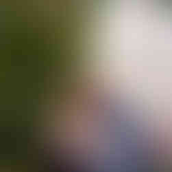 couple snuggles up and looks at the camera smiling surrounded by lush greenery