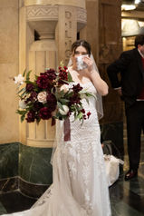 bride holding big bouquet and wiping tears away with hankerchief