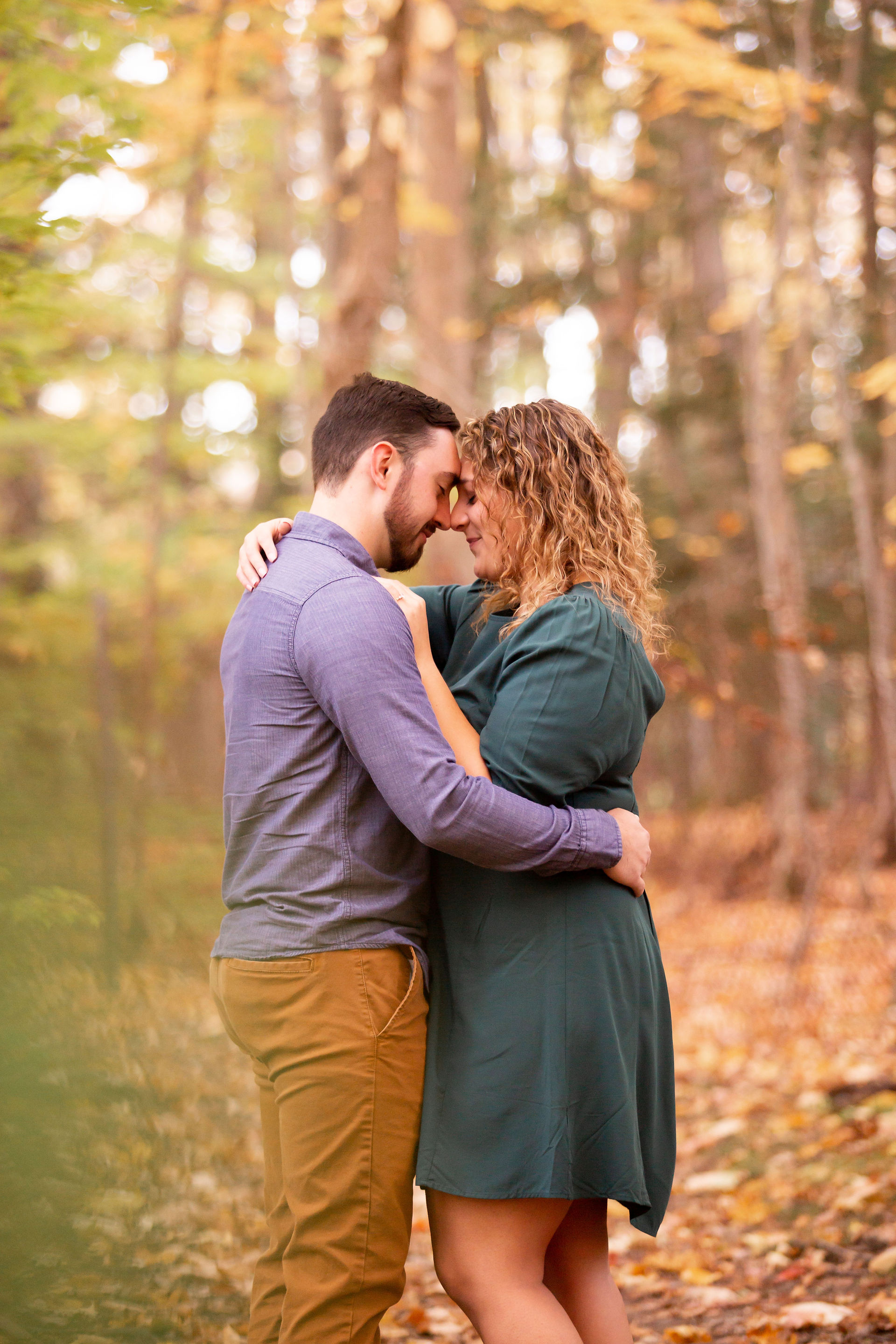 couple stands hugging with fall foliage in background