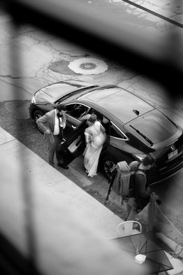 bride and groom getting into car photographed through upstairs window