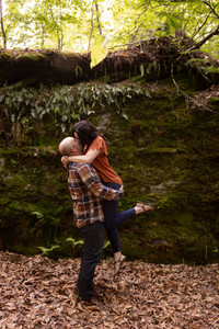man picks up woman in front of boulder and they kiss