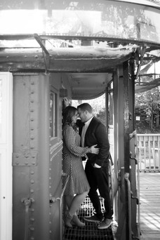 man and woman stand in a train car leaning into one another