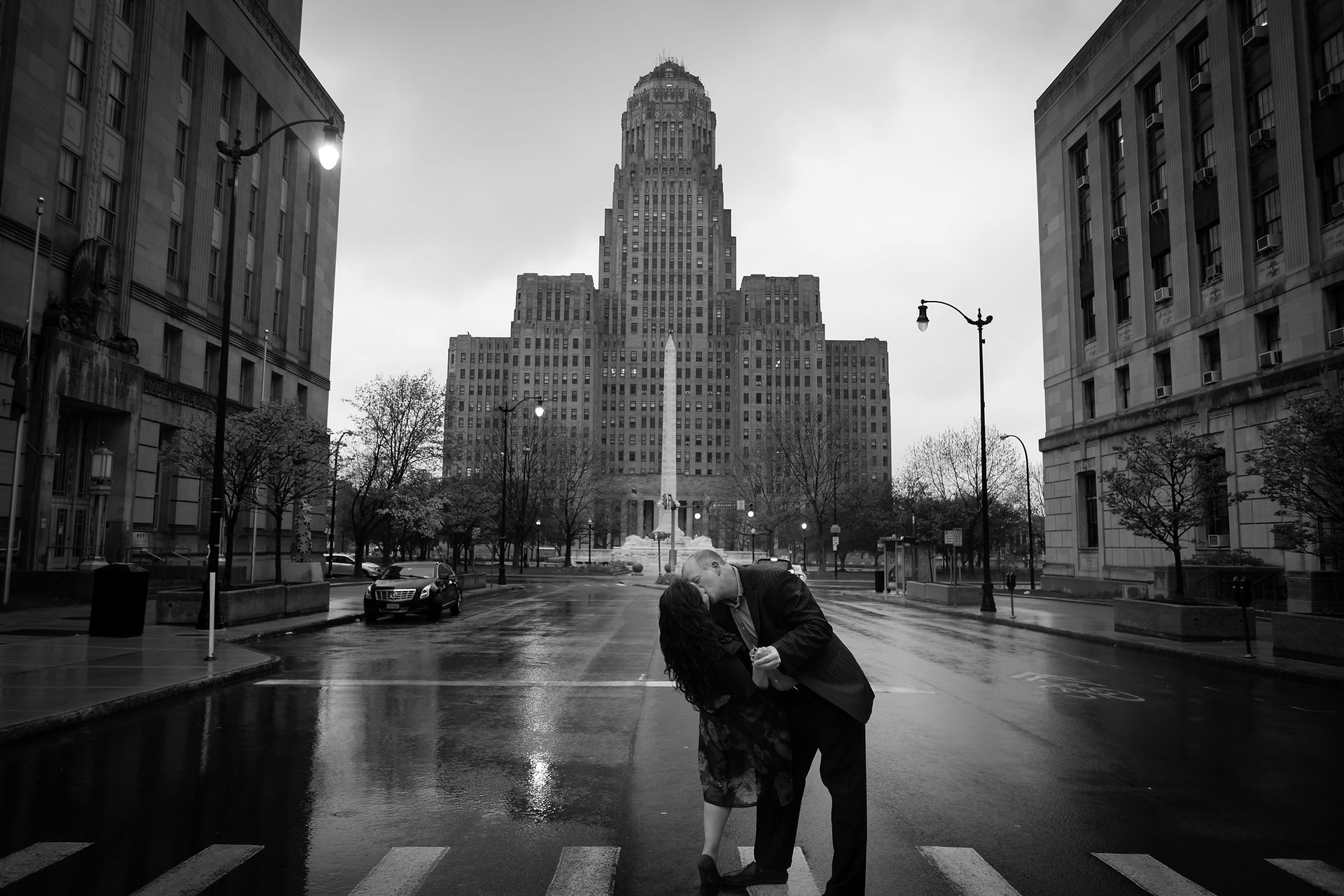 couple does a a kiss in dip with Buffalo City Hall behind them