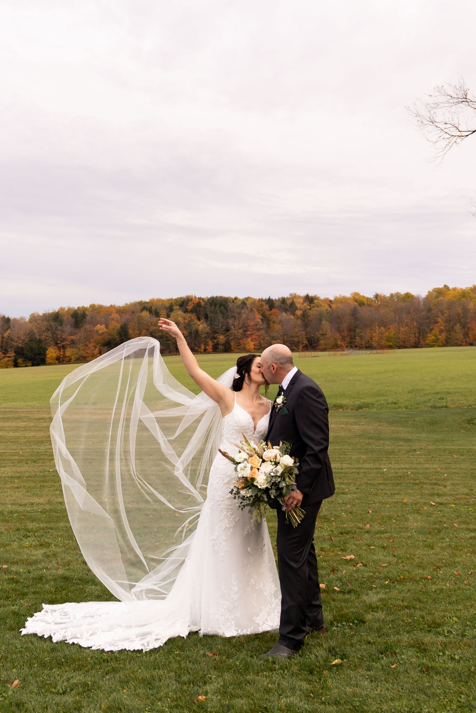 bride throwing veil in air kissing groom