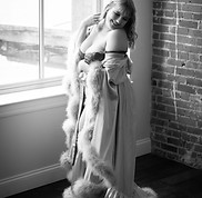 woman in feather lined robe and lingerie looking over shoulder and laughing