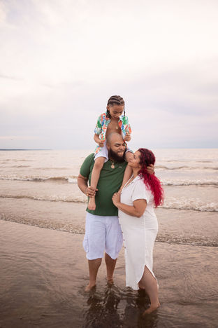 family on beach with kid on dads shoulders