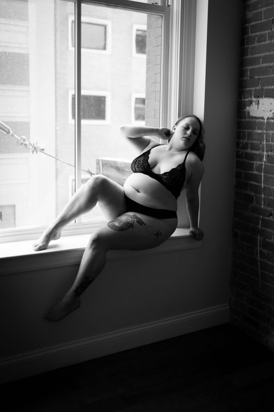 black and white image of boudoir model sitting in oversized window