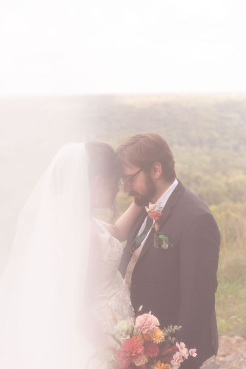 bride and groom stand head to head photographed through veil