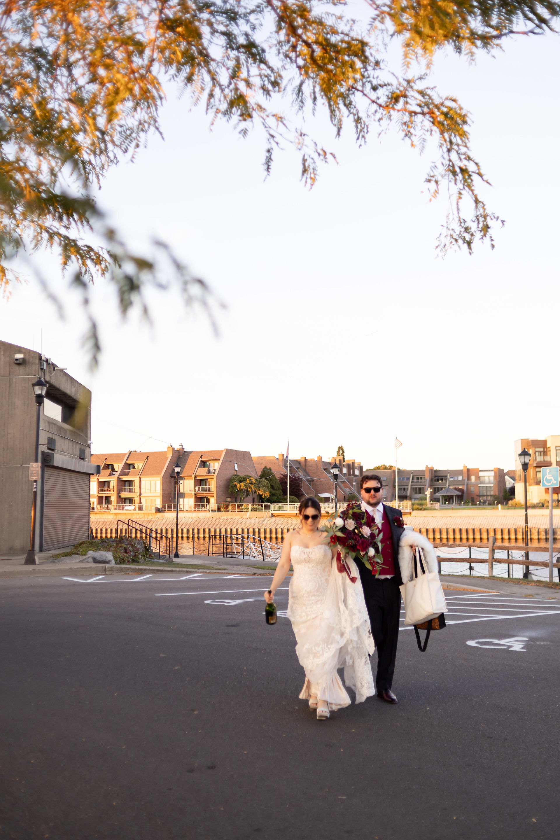 elopement couple walking through parking lot carrying flowers and fur shawl