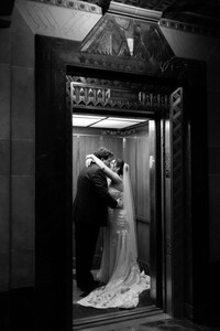 black and white image of bride and groom kissing in an elevator as the door closes