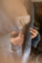 Woman in a denim shirt opens it to reveal a white lace bra in soft warm light.