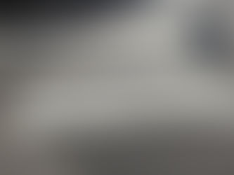 Descripción de la imagen: Cebra peatonal hecha con una pintura con relieve, colocada de manera irregular y desprolija. En el costado derecho, se ve la sombra de un peatón que camina por fuera de esta senda.