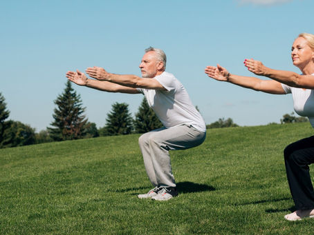 A couple engages in gentle exercises on a grassy field, focusing on movements beneficial for herniated discs.