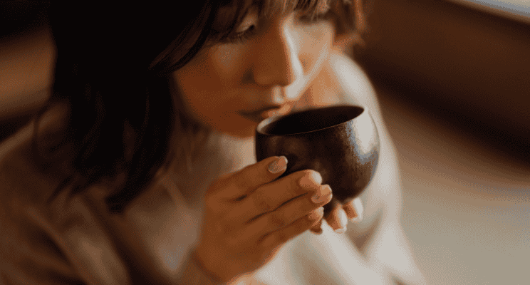 a woman holding a tea cup near her mouth
