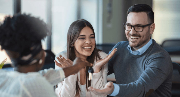three employees enjoying a conversation together as one employee hands keys to the male employee