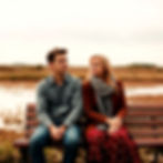 serious and unhappy couple sitting on bench, man looking away from woman, not smiling, bot