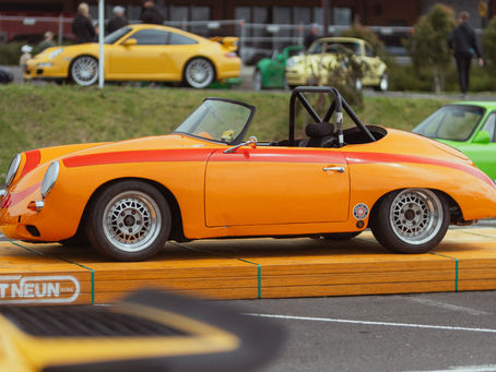 Vintage orange Porsche convertible displayed on a wooden platform at the Artneun “Porsche as Art” exhibition in Melbourne, showcasing design, heritage, and emotion through automotive craftsmanship.