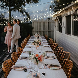 Dinner party table styled with candles, crockery and low floral arrangements in neutral tones