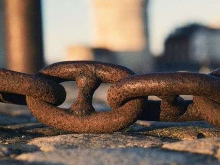 Le parasitisme économique et la concurrence déloyale : une entreprise entravée par des chaînes symbolisant l’exploitation abusive de sa notoriété, de ses investissements ou de ses efforts par un concurrent sans justification légale.