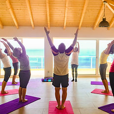 Helles Yoga-Studio mit Meerblick auf den Atlantik: Teilnehmer praktizieren gemeinsam Yoga bei Yolume Yoga Retreat.