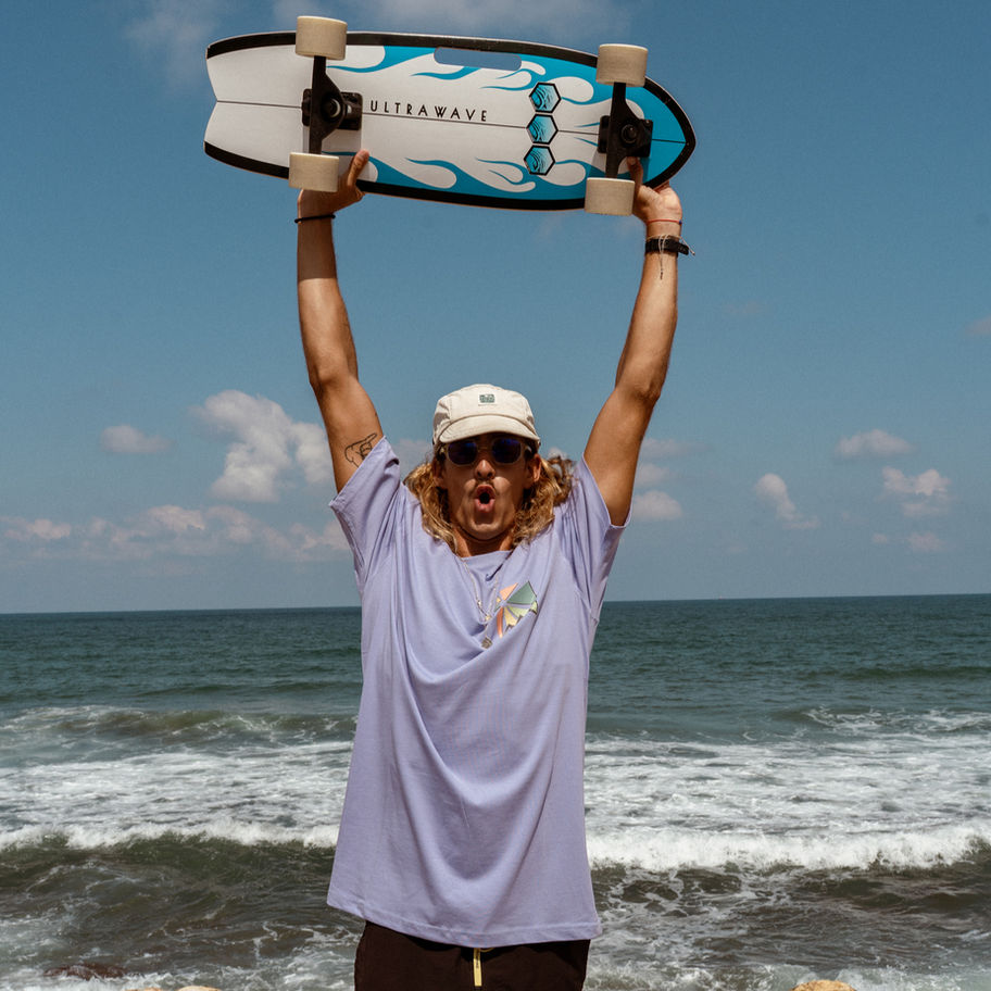 Man holding surfboard, wearing Surf Wagon Tee - Grey - Unisex, at the beach
