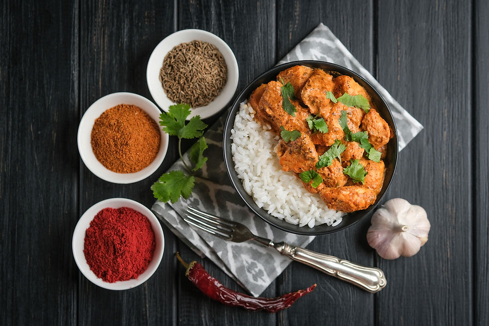 Bowl of spicy asian chicken over rice with 3 spice bowls around it.