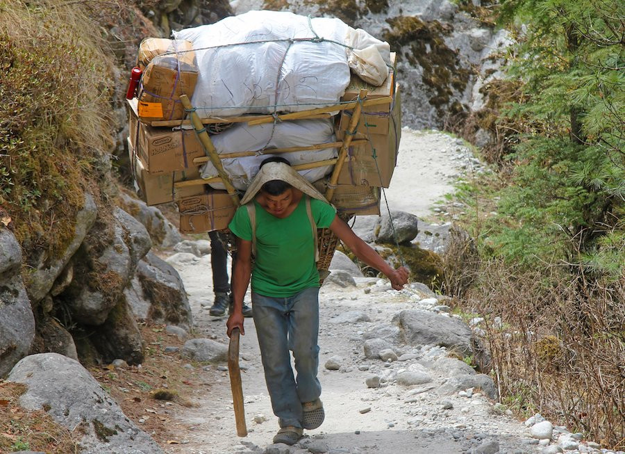 Man carrying a heavy load on his back.