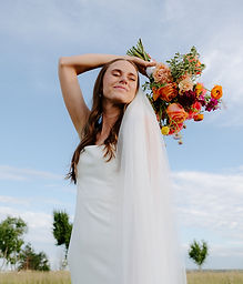 A bride smiling with her eyes closed with her bouquet over her head
