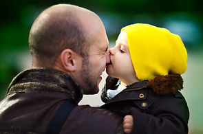 Man holding child as they kiss his nose