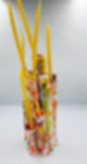 Yellow candles in a multi-tube floral ceramic vase.