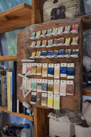 Ceramic glaze test tiles on a wooden board in a studio.