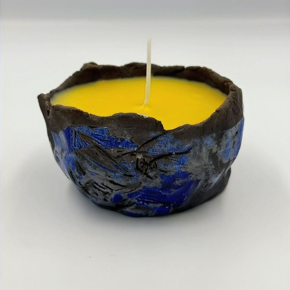 Yellow Bee Raku citrus candle in a textured blue bowl