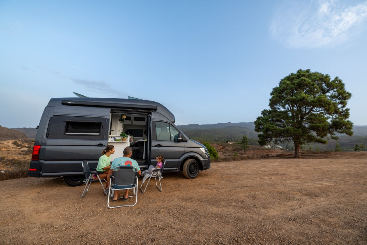 Volkswagen Grand California 600 with solar campervan parked on coastal road.