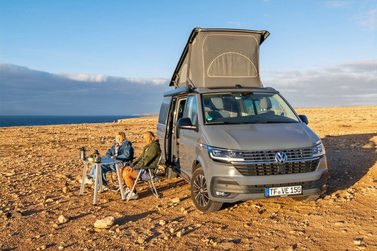 Volkswagen California 6.1 Ocean campervan with camping chairs and table on the coast of Fuerteventura.