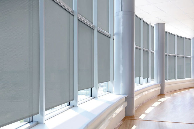 Roller shades cover windows in a modern building with natural light.