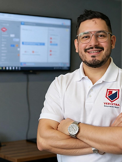 Veristra team member wearing a branded polo shirt beside a computer monitor in the office