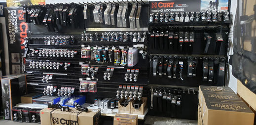 Trailer hitch and towing accessories display at Deer Valley Trailer in Phoenix, Arizona, featuring CURT hitches, ball mounts, hitch balls, weight distribution hitches, and towing equipment.