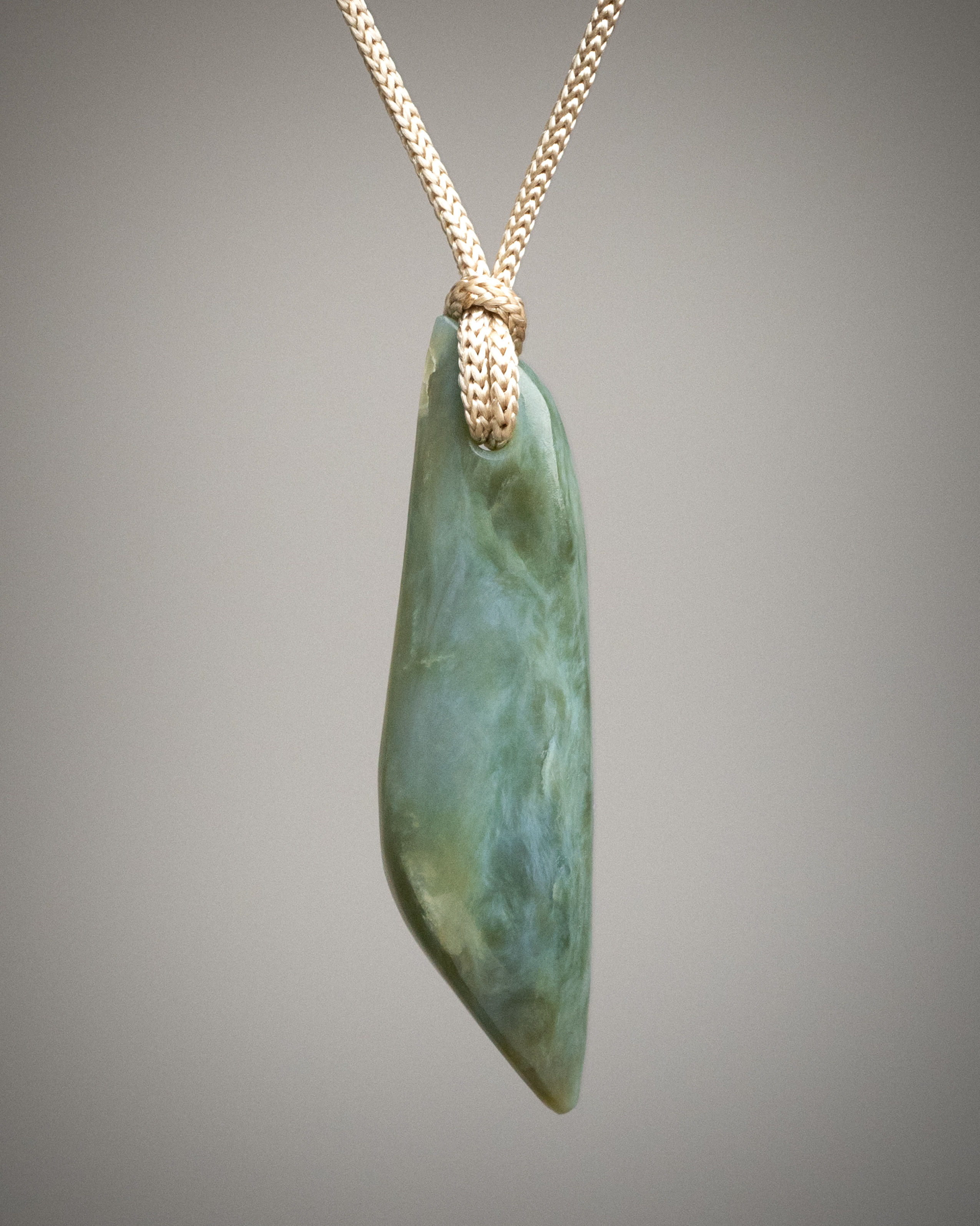 Blue-green nephrite jade drop pendant on tan cord, front view