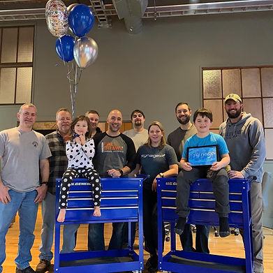 Synagex team photo with two children sitting on blue tool chests