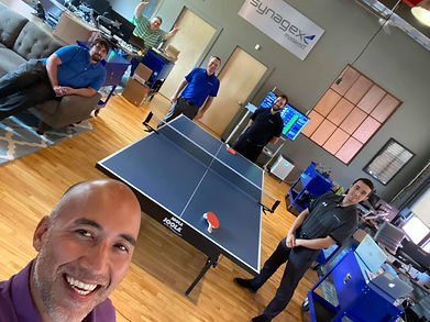 Synagex team photo showing their office lounge with ping pong table